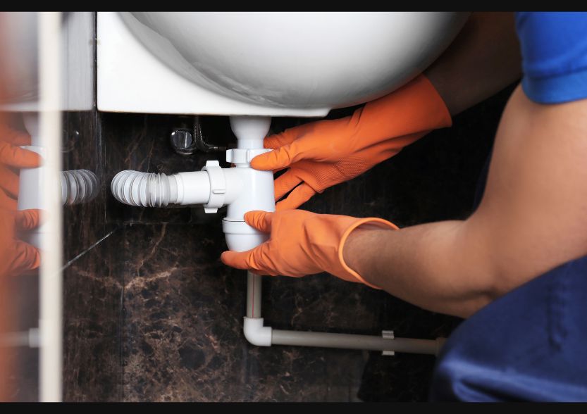 Imagem de encanador profissional consertando um cano.